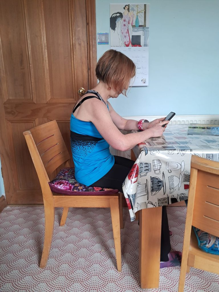 forward bending with osteoporosis. Here the author is sitting, looking at her phone with a rounded back