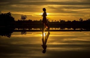 This image is of a lady walking in the countryside with a sunset behind her. Is to illustrate how someone might reach their ideal daily step count